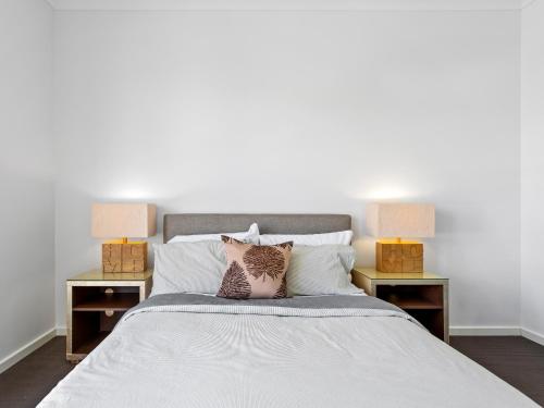 a white bed with two nightstands and two lamps at Sara by Ready Set Stay in Caroline Springs