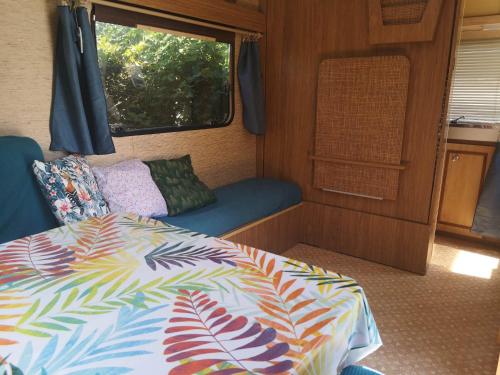 a bedroom with a bed and a window in an rv at Caravane Vintage Esparadenn l'esprit d'antan in Guengat