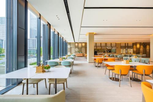 a cafeteria with tables and chairs and windows at EVEN Hotels Shanghai Expo, an IHG Hotel in Shanghai