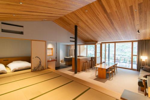 Naoshima Ryokan Roka في ناووشيما: غرفة نوم وغرفة معيشة مع سرير وطاولة