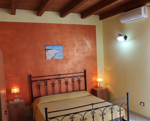 a bedroom with a bed with an orange wall at Affitto breve Puccio A Chiazza Realmonte in Realmonte