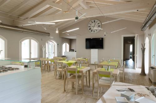 a restaurant with tables and chairs and a clock on the wall at Bianco Hotel in Primaluna