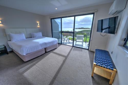 Schlafzimmer mit einem Bett, einem TV und einem Balkon in der Unterkunft Diamond Island Resort & Bicheno Penguin Show in Bicheno