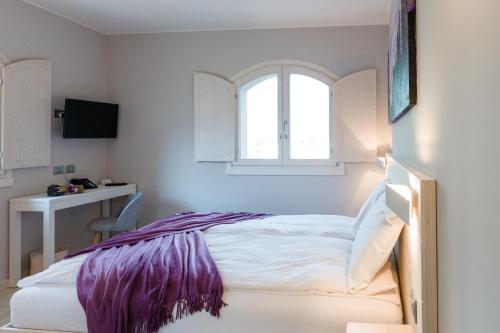 a bedroom with a bed and a window at Bianco Hotel in Primaluna
