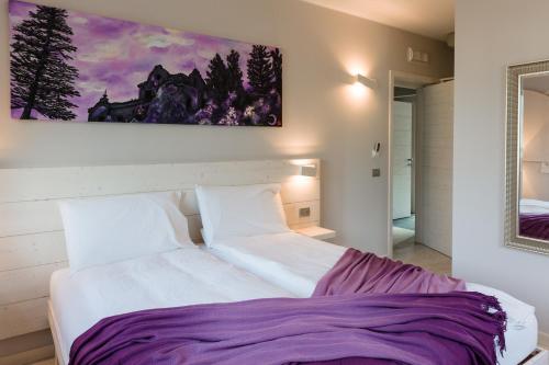 a bedroom with a white bed with a painting on the wall at Bianco Hotel in Primaluna