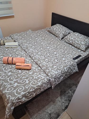 - un lit avec une couette grise et blanche et 2 livres dans l'établissement Apartman Banja Koviljaca, à Banja Koviljača