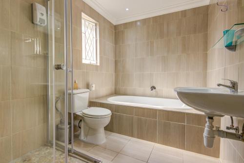 Edenvale Guest House في ايدنفيل: حمام مع مرحاض ومغسلة وحوض استحمام