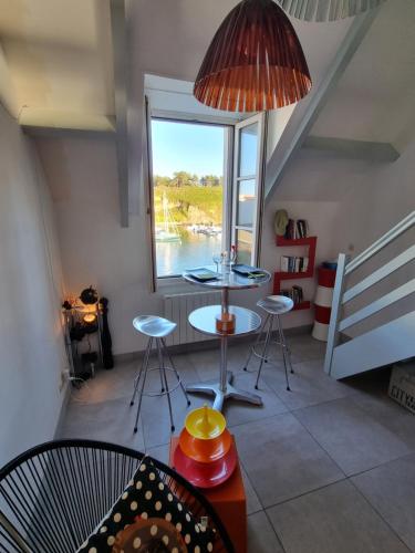 une chambre avec une table, des chaises et une fenêtre dans l'établissement LOC'MARIA, à Sauzon