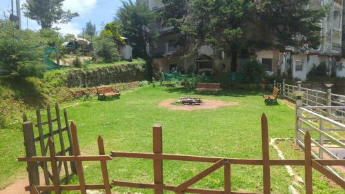a yard with a fence and a park with benches at Vpr residency ooty in Ooty