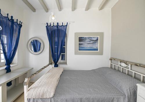 1 dormitorio blanco con cortinas azules y 1 cama en Josephine's Kardiani House, en Kardhianí