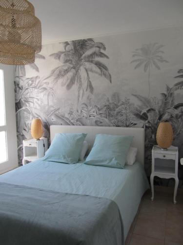 - une chambre avec un lit recouvert de palmiers dans l'établissement Appartement Les Cigales Rez de Jardin à 10mn des plus belles plages, à Hyères