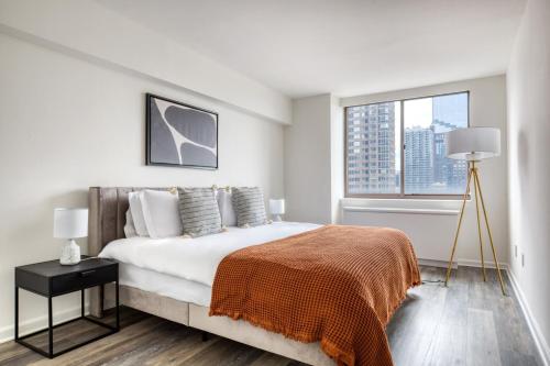 a white bedroom with a large bed and a window at Midtown West 2br w doorman gym wd nr Times Sq NYC-1068 in New York