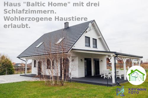 a white house with a porch and a sign that reads hasmt at Dom Wakacyjny Baltic Home & Dom Baltic Home Garden Inn in Zastań