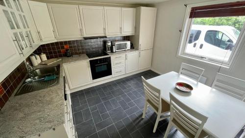 une cuisine avec des armoires blanches et une table avec des chaises dans l'établissement EG Apartment, à Leknes