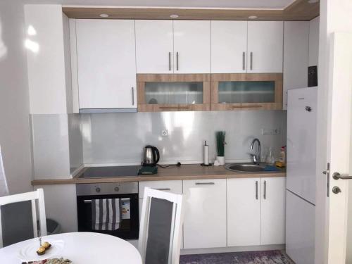 a kitchen with white cabinets and a sink and a table at Luxury apartments - Otoka Sarajevo in Sarajevo