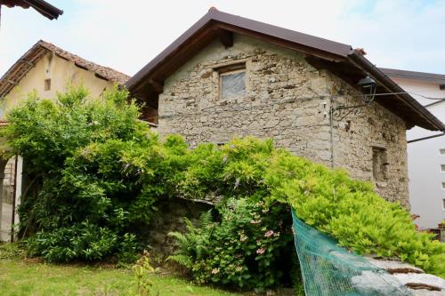 uma casa de pedra com arbustos à frente em Casa di Carla em Lauco