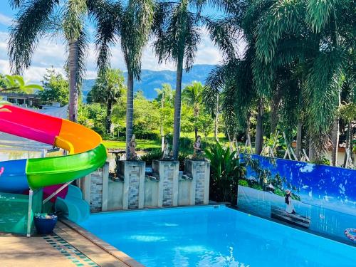 a pool with a slide in a resort with palm trees at Pool Villa Kiang Na Mae Rim in Mae Rim