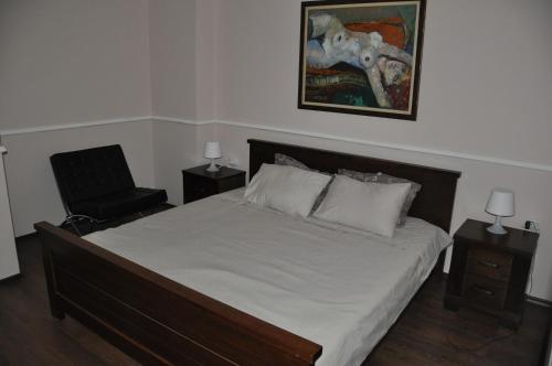 a bedroom with a bed and a chair and a painting at Marko's Place Apartment in Skopje