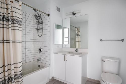 a white bathroom with a toilet and a sink and a tub at West Loop 2br w theater gym nr restaurant row CHI-950 in Chicago