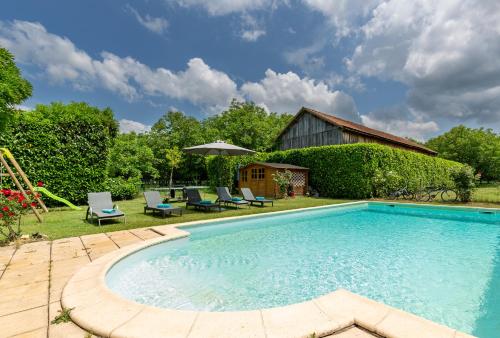 uma piscina num quintal com cadeiras e um guarda-sol em The Cottage and The Barn at Les Chouettes em Trémolat