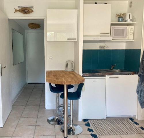uma cozinha com armários brancos e um balcão com bancos em Joli Studio em Grand-Village-Plage