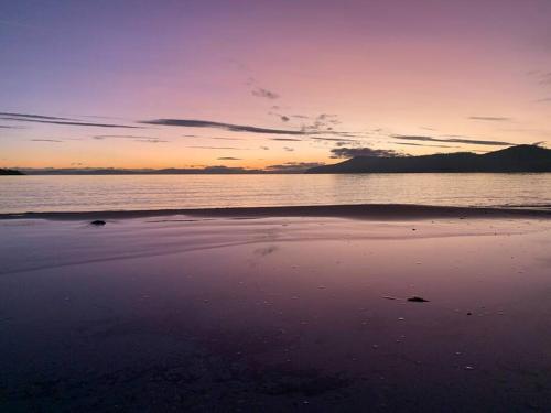 a sunset on a beach with the ocean at Beachfront self contained studio in White Beach