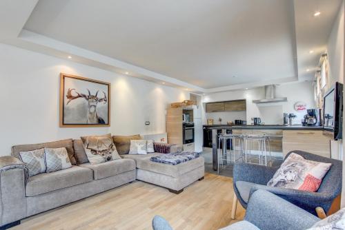 un salon avec un canapé et des chaises et une cuisine dans l'établissement Les Berberis - Snow and Trek, à Morzine
