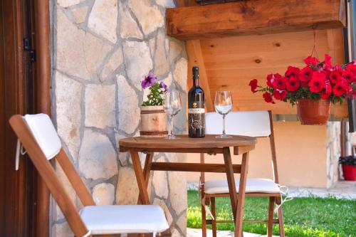 a table with a bottle of wine and two chairs at Cottages Big bear in Žabljak