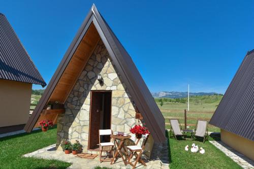 a small cottage with a table and chairs in a yard at Cottages Big bear in Žabljak