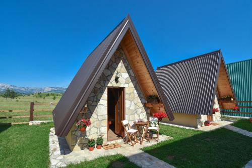 a small cottage with a pitched roof and a table and chairs at Cottages Big bear in Žabljak