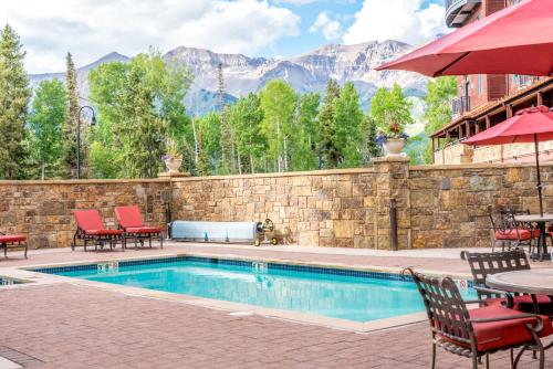 uma piscina com cadeiras e mesas e uma parede de pedra em Bear Creek Lodge 207B Hotel Room em Telluride