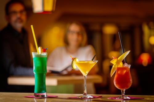 three cocktails sitting on a table in a bar at Hotel Vier Jahreszeiten am Schluchsee in Schluchsee