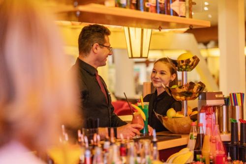 a man and a woman standing at a bar at Hotel Vier Jahreszeiten am Schluchsee in Schluchsee