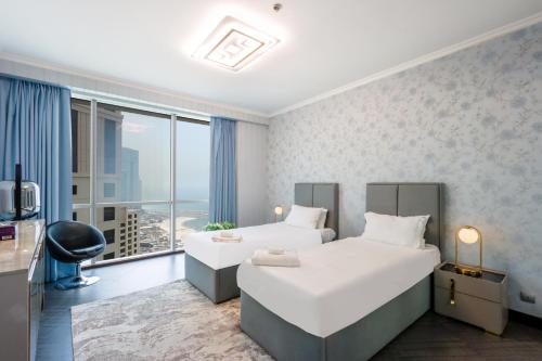 a hotel room with two beds and a large window at Heart of JBR - SEA VIEW - Upgraded 3 Bedroom Suite in Dubai
