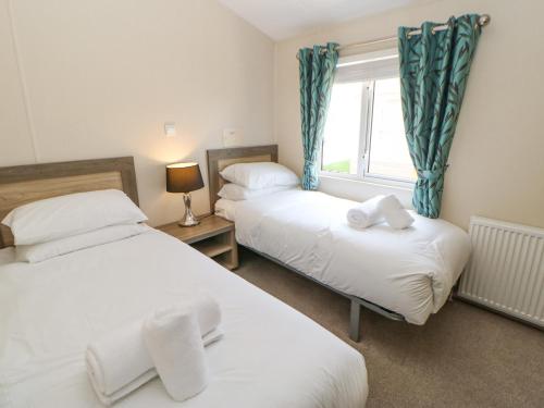 2 Betten in einem kleinen Zimmer mit Fenster in der Unterkunft 36 Raven's Rest in Carlisle