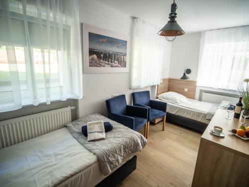 a bedroom with a bed and a chair and a table at Sanatorium Mewa in Kołobrzeg