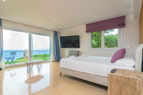 PuigderrósにあるVilla Luna Suitesの海の景色を望むベッドルーム1室(大型ベッド1台付)