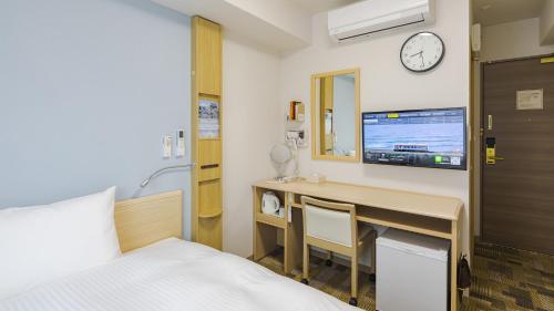 Toyoko Inn Tokuyama-eki Kita-guchi في Shunan: غرفة في الفندق بها سرير ومكتب وتلفزيون