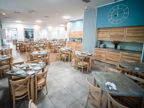 a restaurant with tables and chairs and a clock on the wall at Sanatorium Mewa in Kołobrzeg