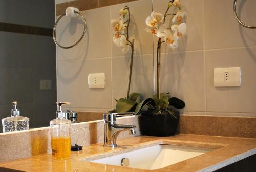a bathroom counter with a sink with a vase of flowers at Apartamento Virgilio Arias in Antofagasta