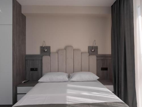 a bedroom with a large white bed with two pillows at Hotel Diman in Dobra Voda
