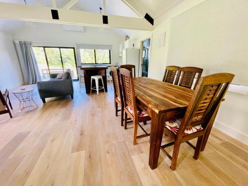 a dining room and living room with a wooden table and chairs at Stunning 2 bedroom Guesthouse in Tamahere