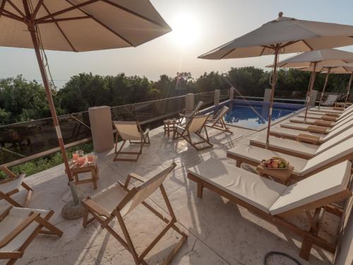 a group of chairs and umbrellas next to a swimming pool at Hotel Diman in Dobra Voda