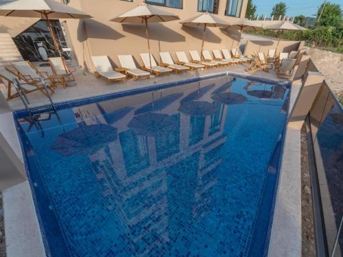 a swimming pool with chairs and umbrellas at Hotel Diman in Dobra Voda