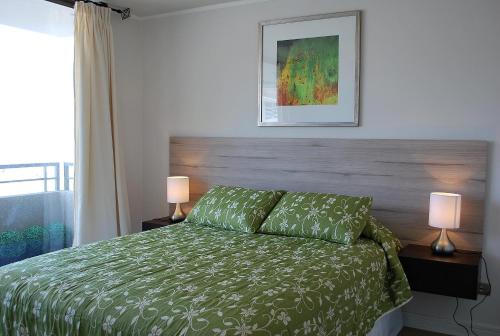 1 dormitorio con 1 cama con edredón verde y 2 lámparas en Apartamento Virgilio Arias, en Antofagasta