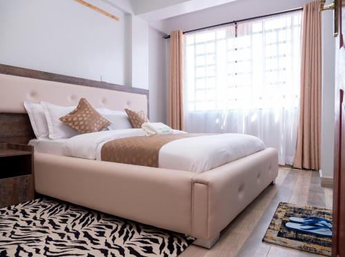 a bedroom with a large bed and a window at Havan Furnished Apartments- Hyrax Hill in Nakuru