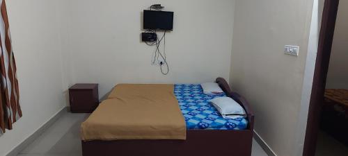 a small bedroom with a bed with a tv on the wall at Adithya Residency Guruvayur in Guruvāyūr