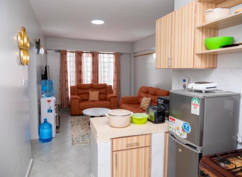 a kitchen with a refrigerator and a living room at Havan Furnished Apartments- Hyrax Hill in Nakuru