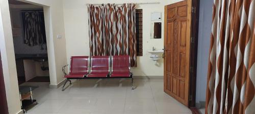 a red chair sitting in a room with a door at Adithya Residency Guruvayur in Guruvāyūr