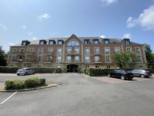 un gran edificio con coches estacionados en un estacionamiento en Tulip Inn Honfleur Residence & Spa, en Honfleur